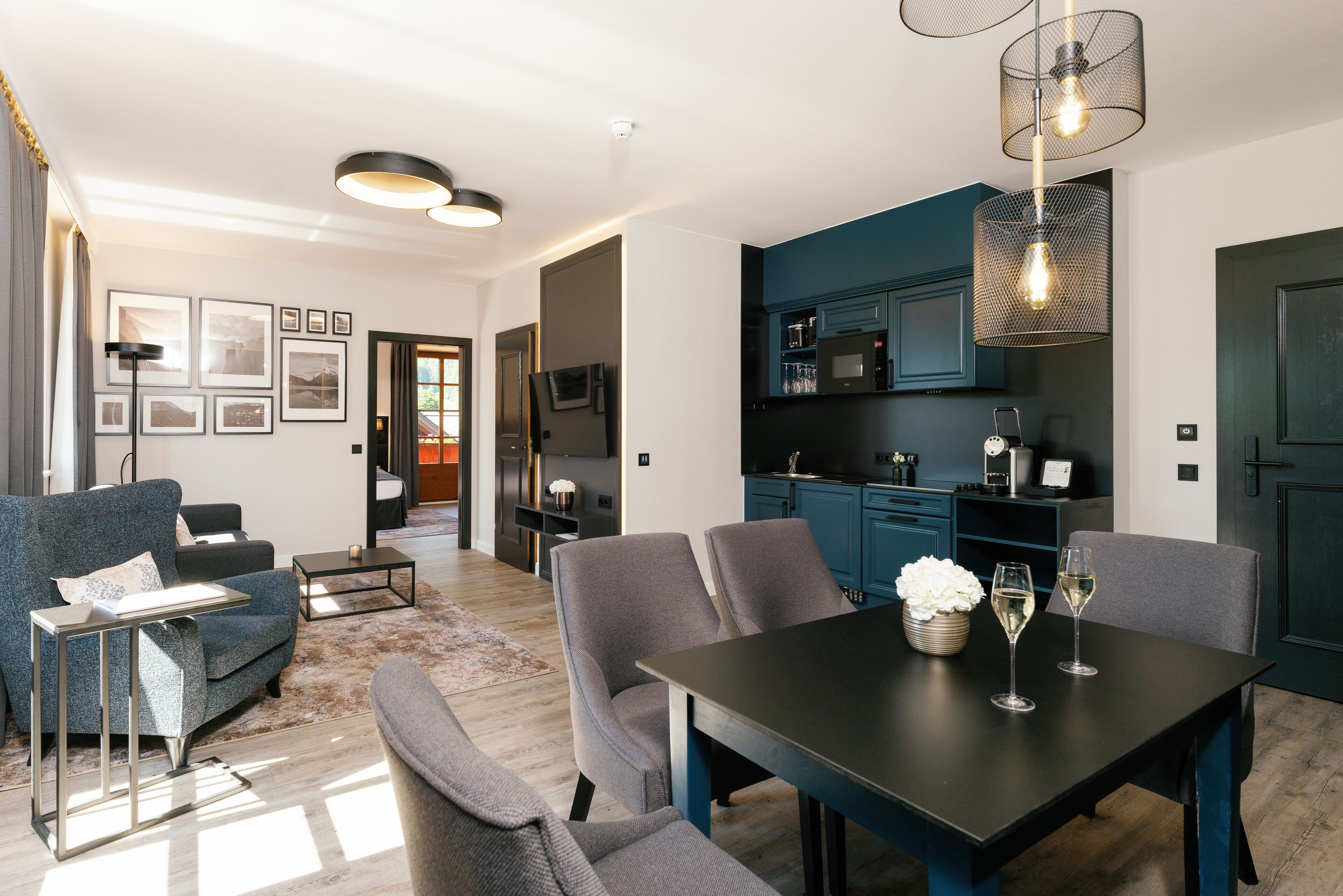 A modern living room with a sofa, chairs, a coffee table, and a dining table with two wine glasses.