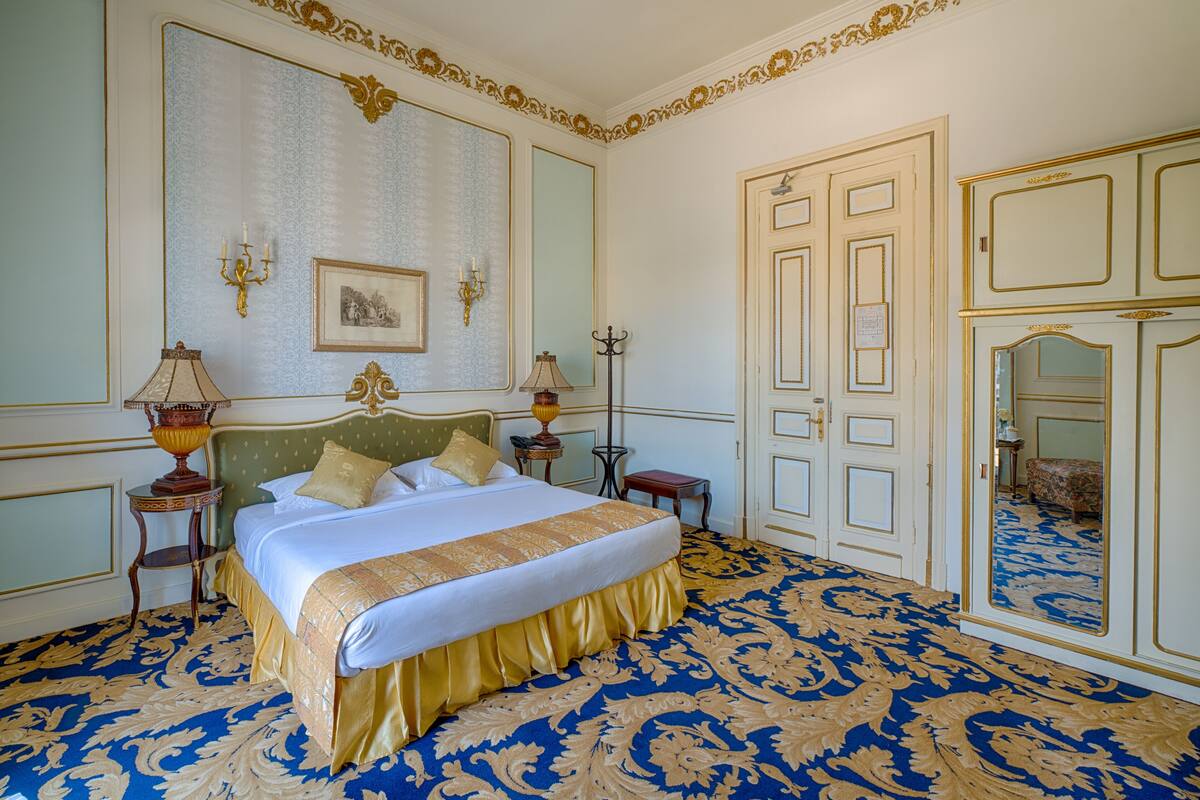 A large bed with a green headboard, two bedside tables, and a mirror.