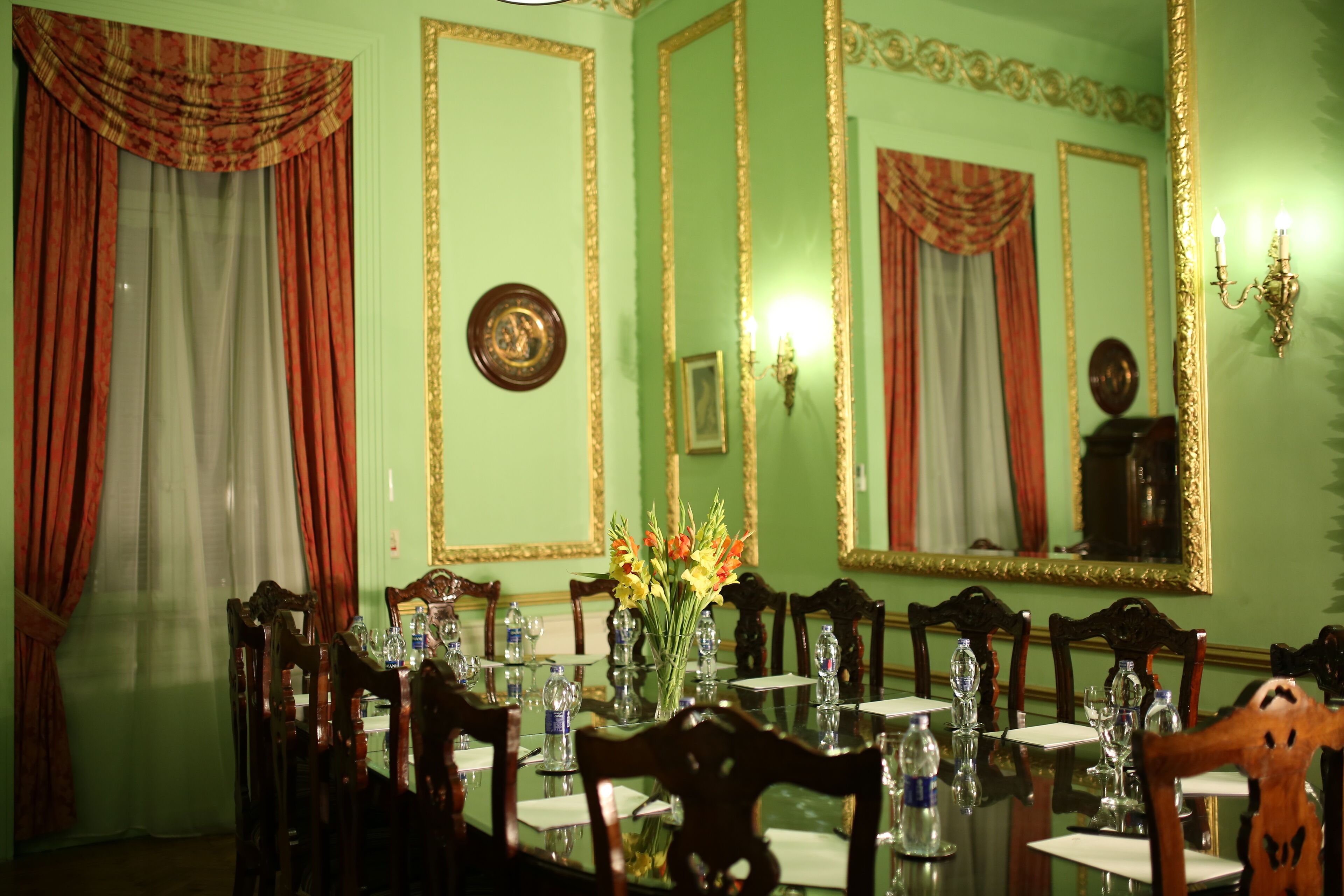 A formal dining room with a long table, chairs, and a vase of flowers.