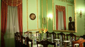 A formal dining room with a long table, chairs, and a vase of flowers.