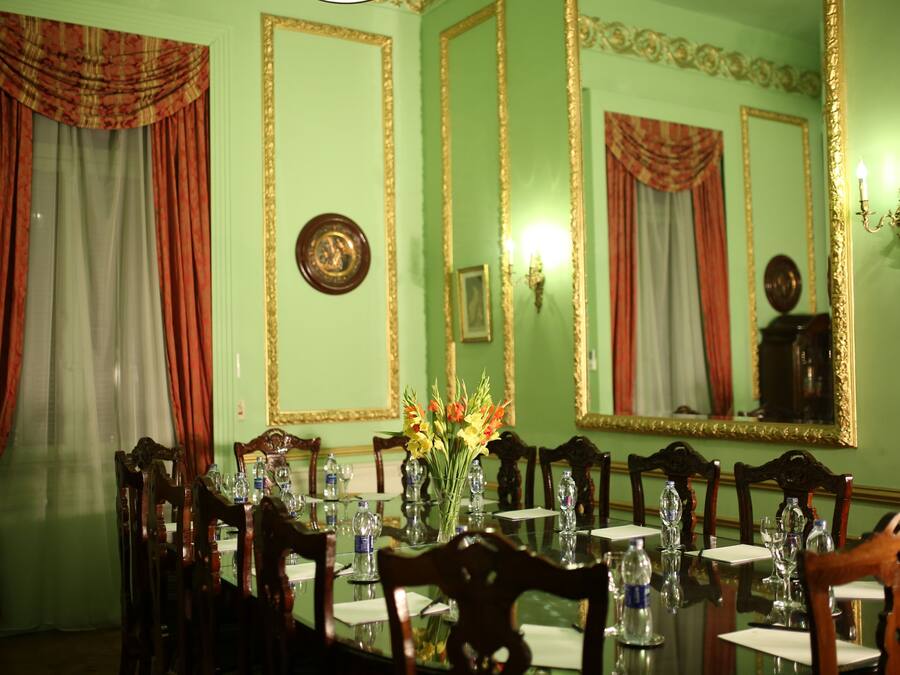 A formal dining room with a long table, chairs, and a vase of flowers.
