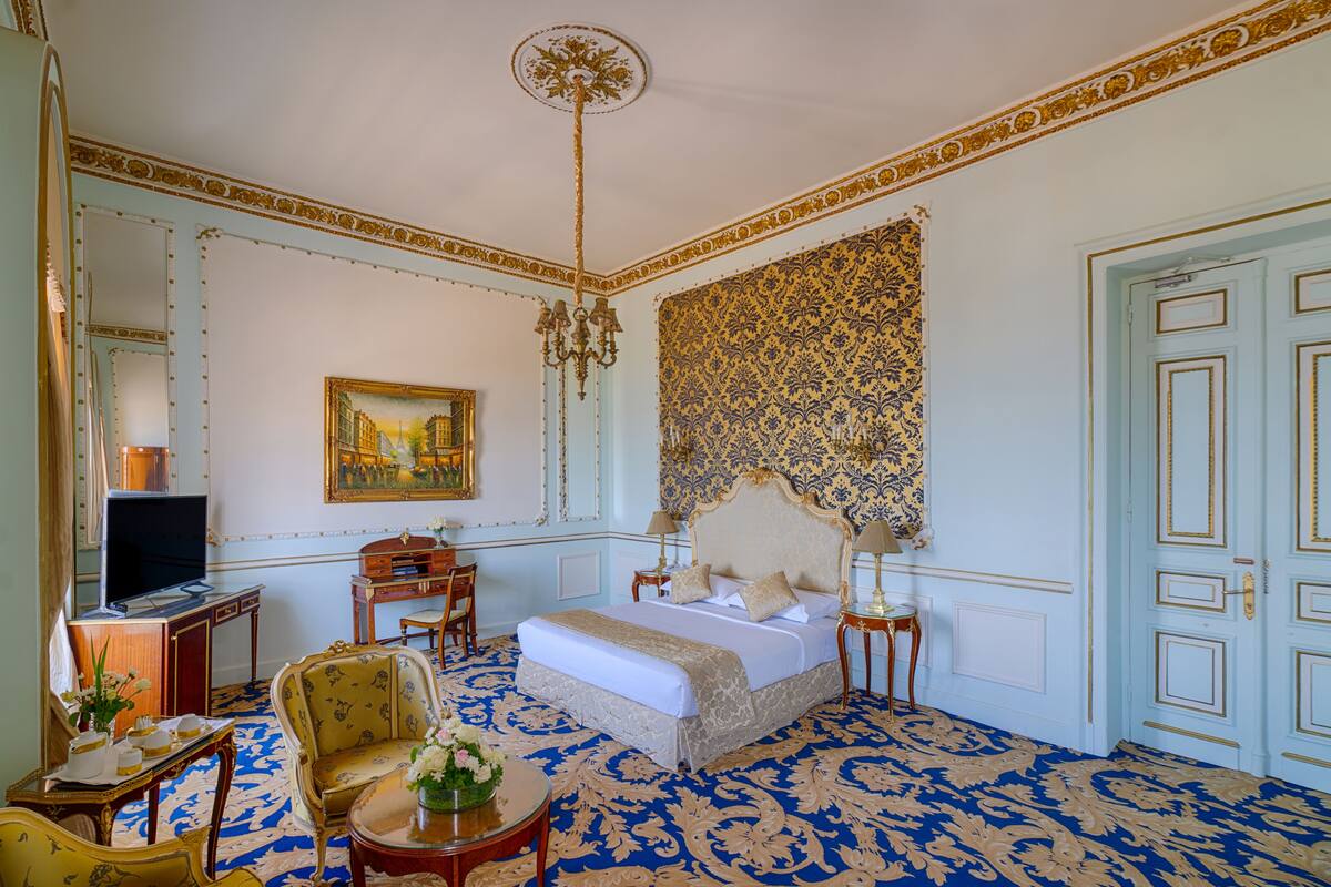 A spacious bedroom with a large bed, a television, a desk, and a chair.