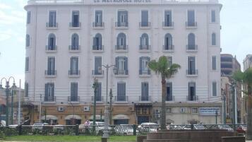 Un hotel grande de varios pisos con un estilo arquitectónico clásico, que cuenta con una entrada central y múltiples balcones.