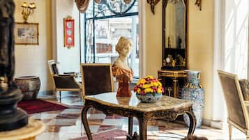 Een luxueuze lobby met een marmeren vloer, decoratief meubilair en een borstbeeld.