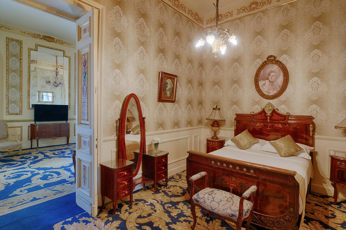 A bedroom with a large bed, a mirror, a dresser, and a chandelier.
