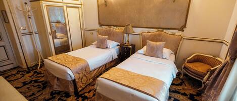 A hotel room with two beds, a chair, a lamp, and a mirror.