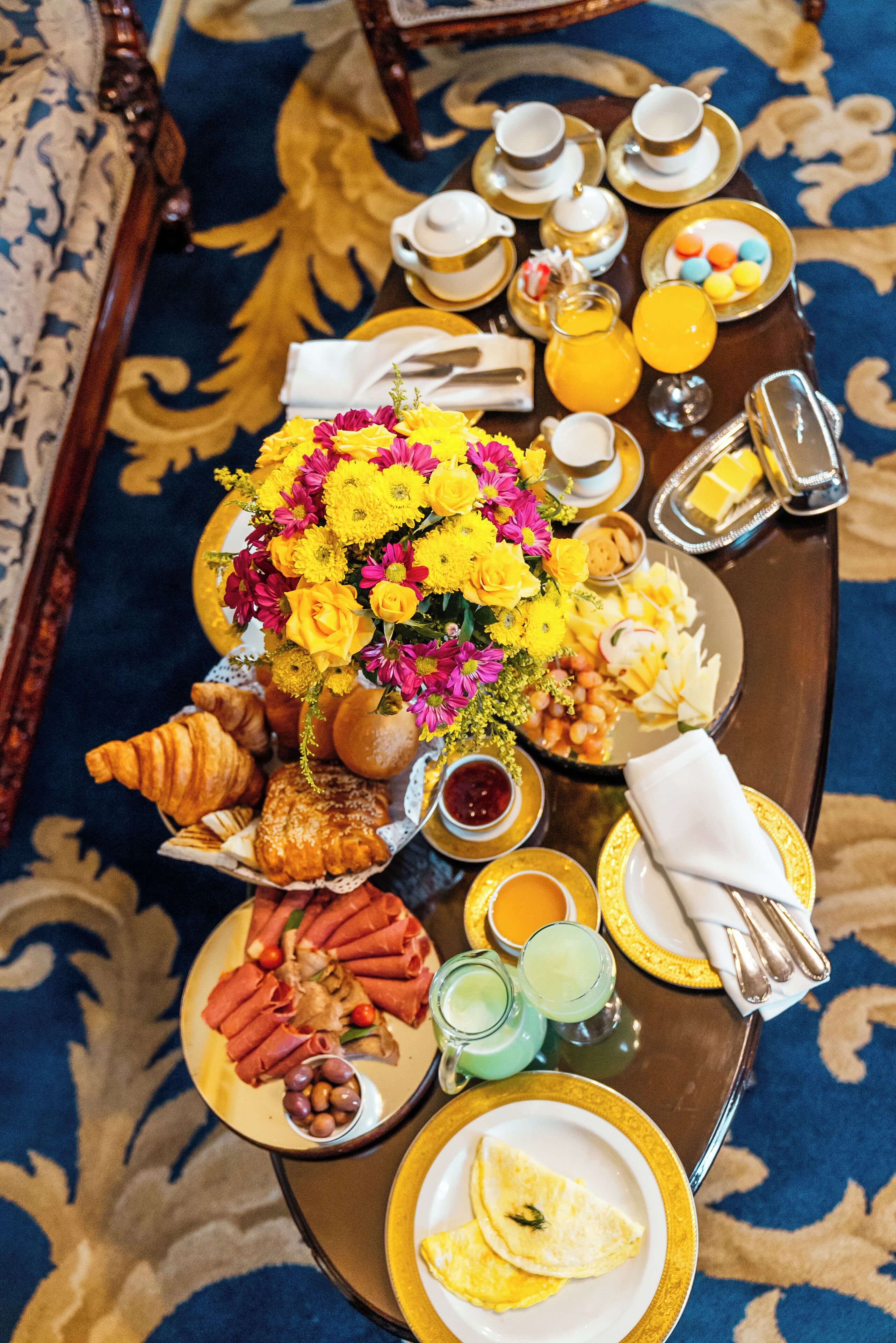 Un bufé de desayuno con una variedad de alimentos, bebidas y un centro de mesa floral.
