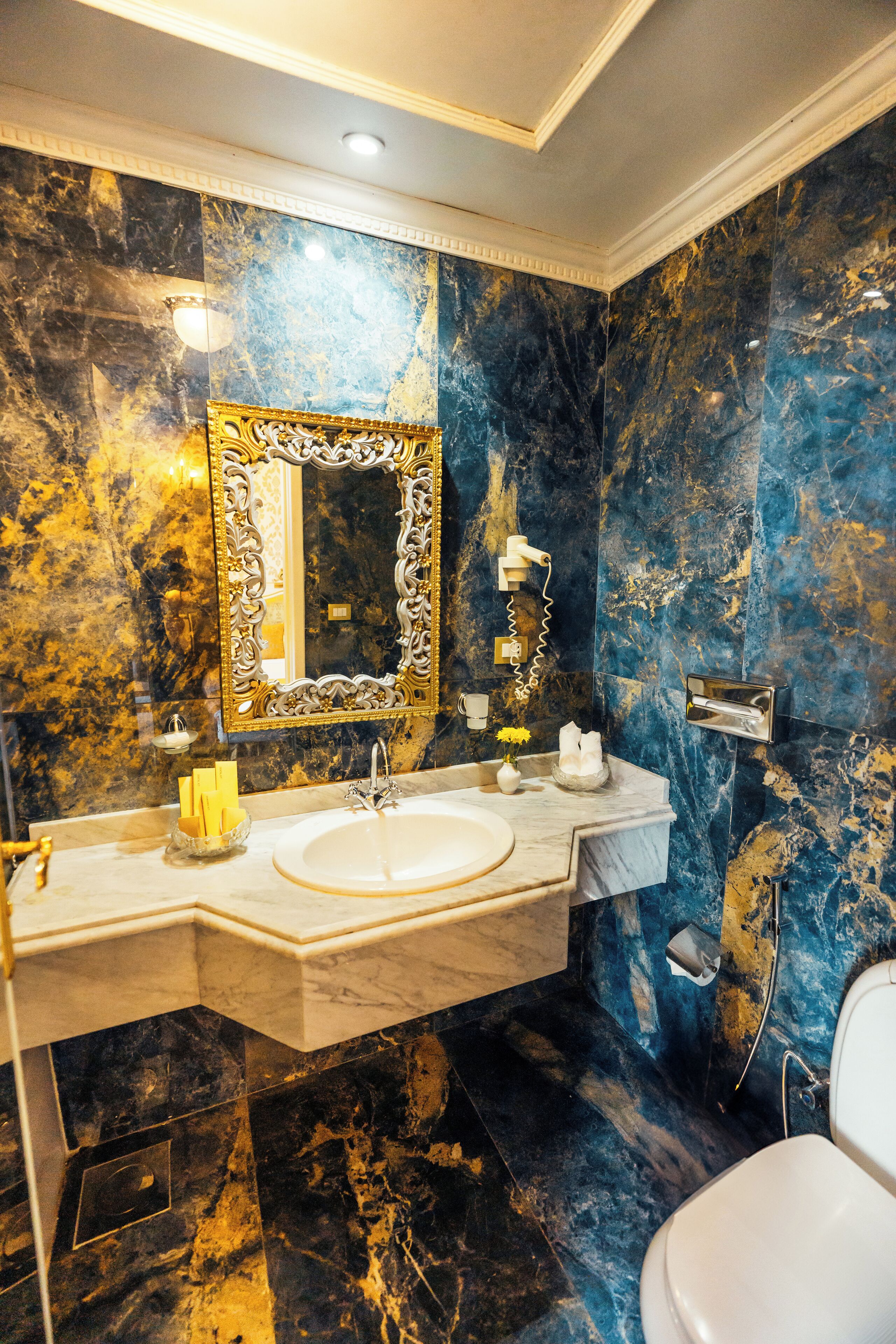 A bathroom with a marble vanity, a large mirror, and a toilet.