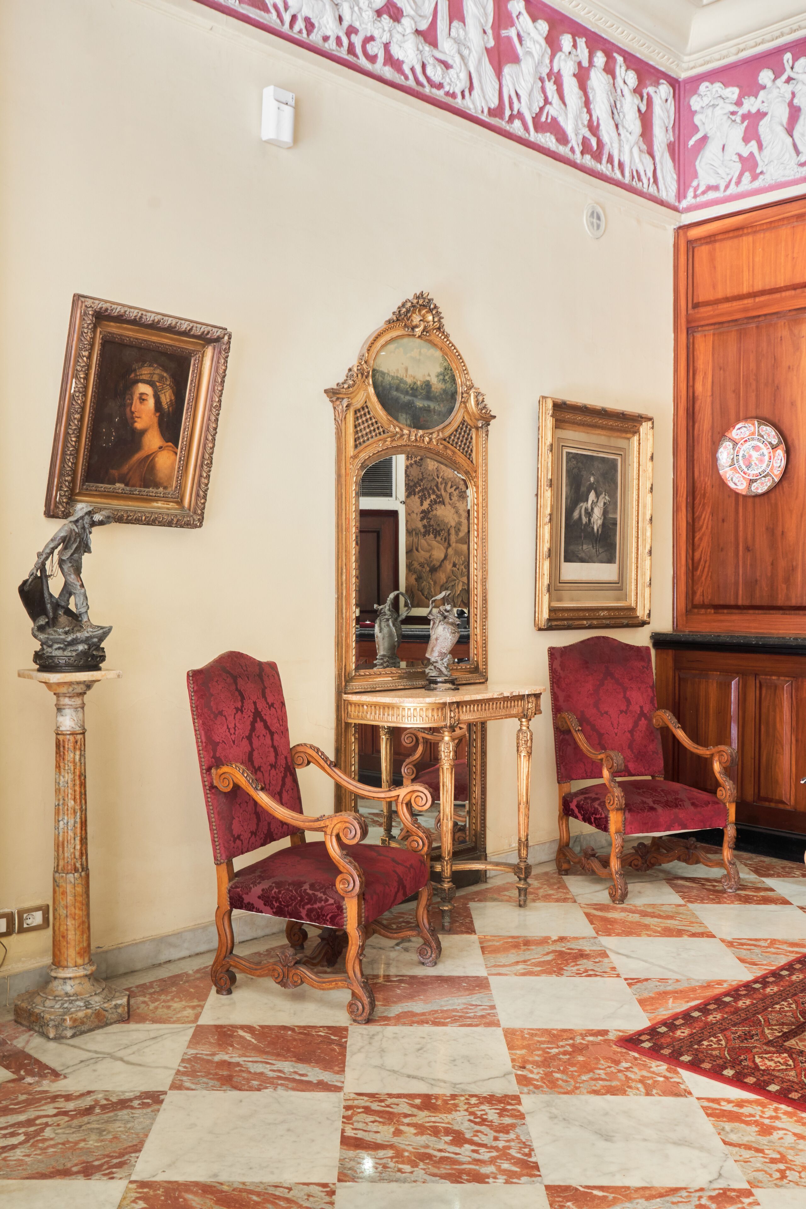 Una habitación con muebles ornamentados, piso de cuadros y un panel decorativo en la pared.