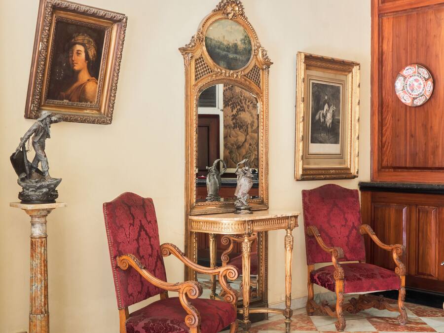 Una stanza con arredi elaborati, pavimento a scacchi e pannello decorativo.