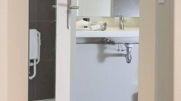 Un baño moderno con ducha, lavamanos y espejo.