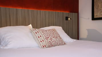 Een net opgemaakt bed met witte lakens en een decoratief kussen.
