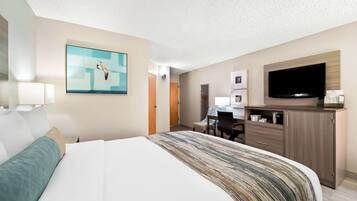 Habitación de hotel con una cama grande, televisión, escritorio con silla y un cuadro en la pared.