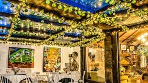 An indoor dining area with tables and chairs, a mural, and a brick wall.