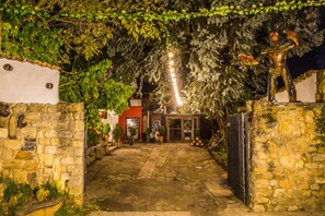 A stone-walled courtyard with a metal gate, a statue, and a building with a glass door in the background. - LA COLINA Hotel Cottage (Bogotá)