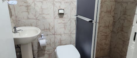 A bathroom with a sink, toilet, and shower stall.