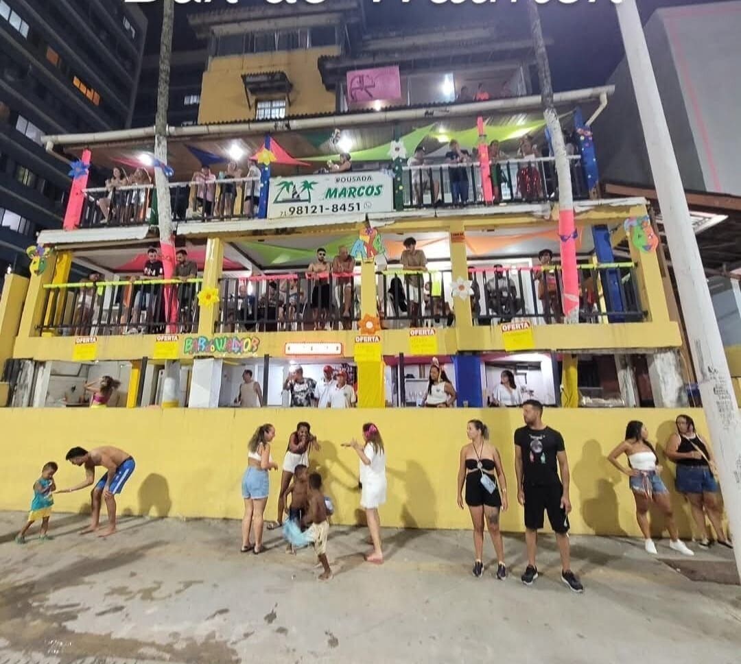 Un edificio de varios pisos con balcones, un letrero que dice 'Browllab' y un cartel con el nombre 'MARCOS'.