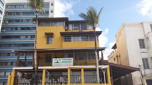 Un edificio de varios pisos con fachada amarilla, balcones y un letrero que dice 'Pousada Marcos'.