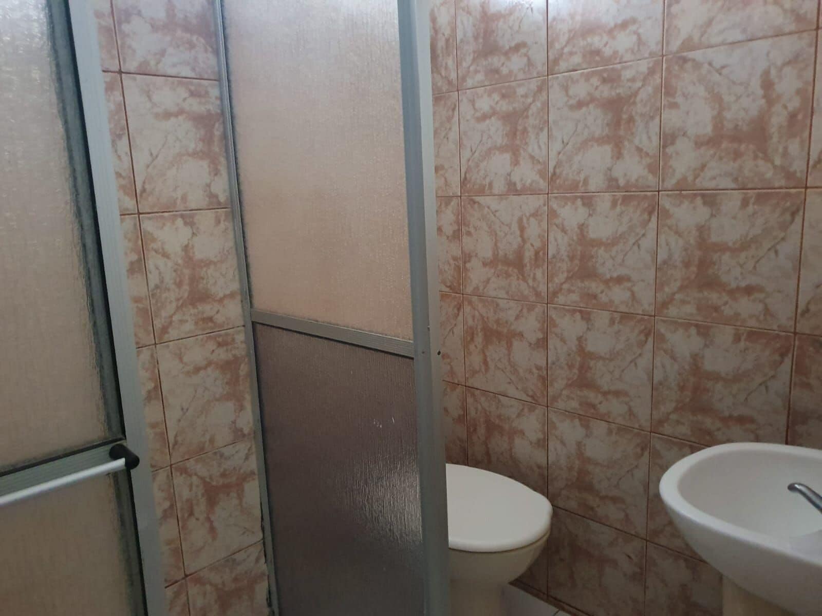 A bathroom with a toilet, a sink, and tiled walls.