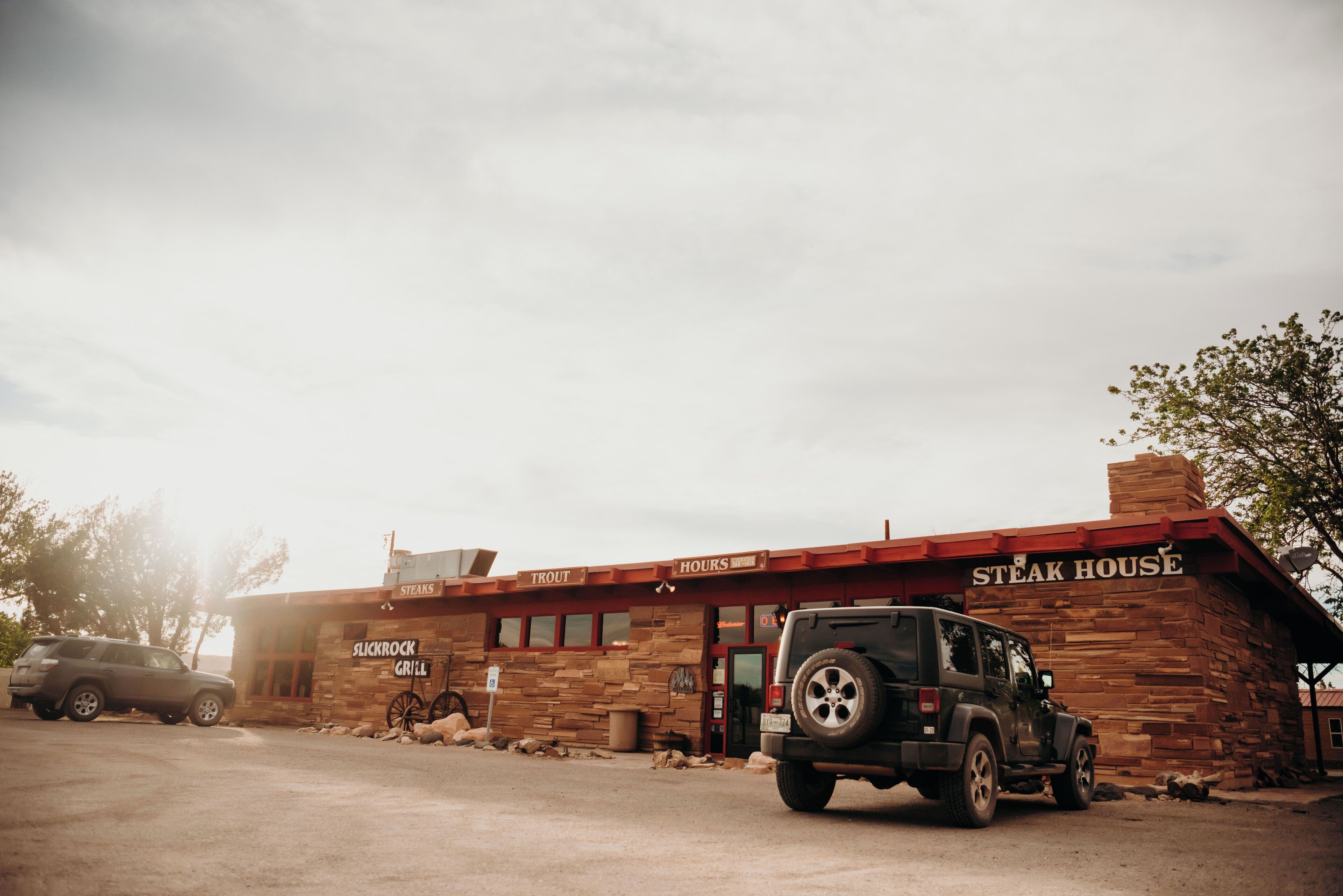 Un edificio de ladrillo con un letrero que dice 'Steak House' y un Jeep estacionado adelante.