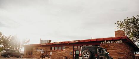 Un edificio de ladrillo con un letrero que dice 'Steak House' y un Jeep estacionado adelante.