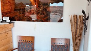 A room with two wooden chairs with patterned upholstery, a large wall mural of a starry night sky and landscape, and a decorative bamboo arrangement. - Whispering Sands Motel (Hanksville)