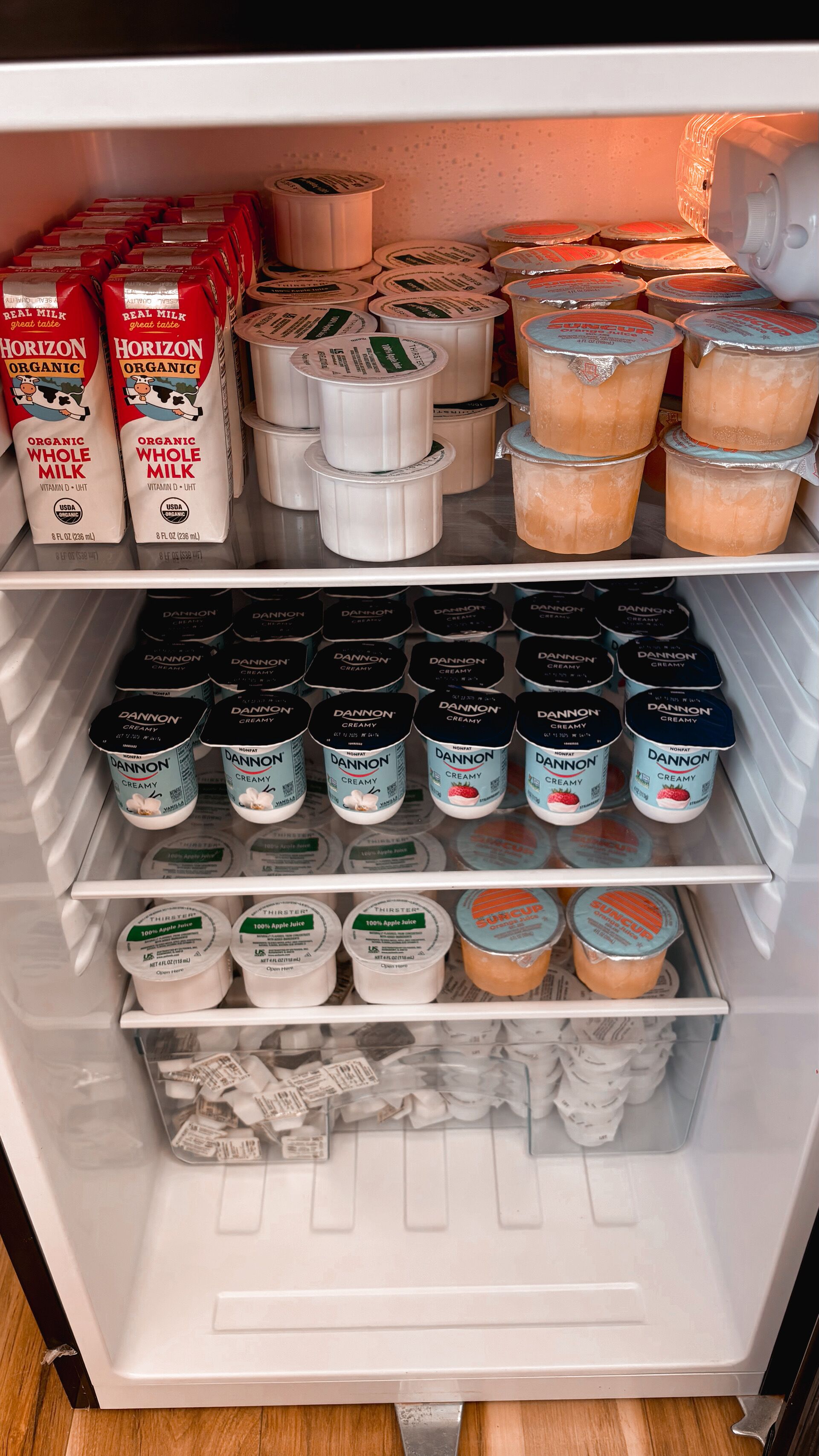 Un refrigerador repleto de diversos productos lácteos, incluyendo leche entera orgánica Horizon Organic, Dannon Creamy y SuCup.