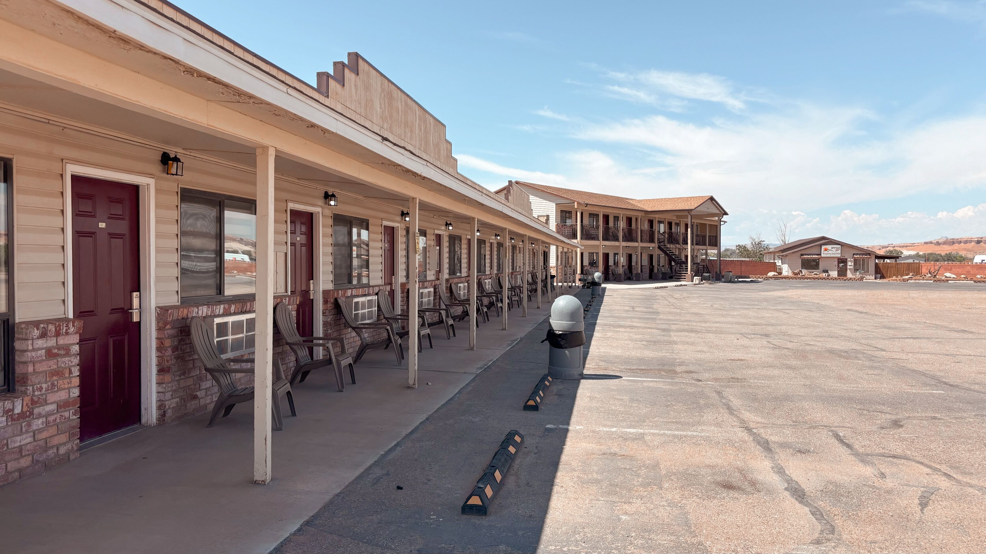 A motel with multiple rooms, a covered outdoor seating area, and a parking lot.