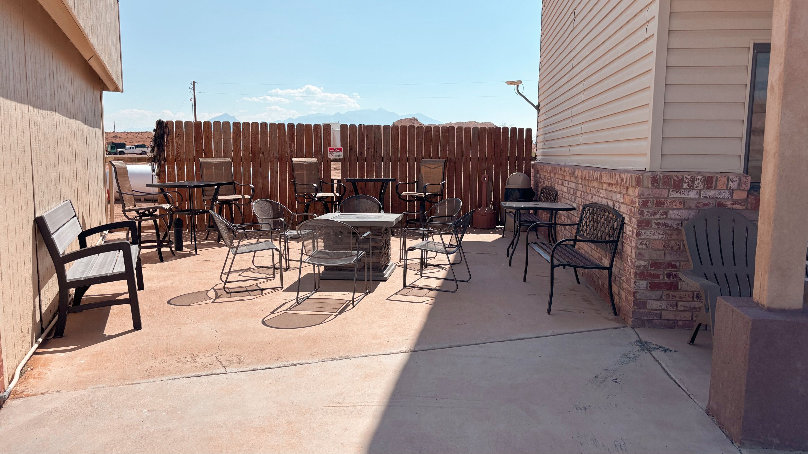 An outdoor patio with tables and chairs, a barbecue grill, and a view of mountains in the background.