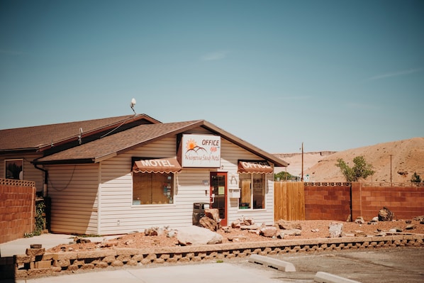 A two-story building with a sign indicating it is a motel and office. - Whispering Sands Motel (Hanksville)
