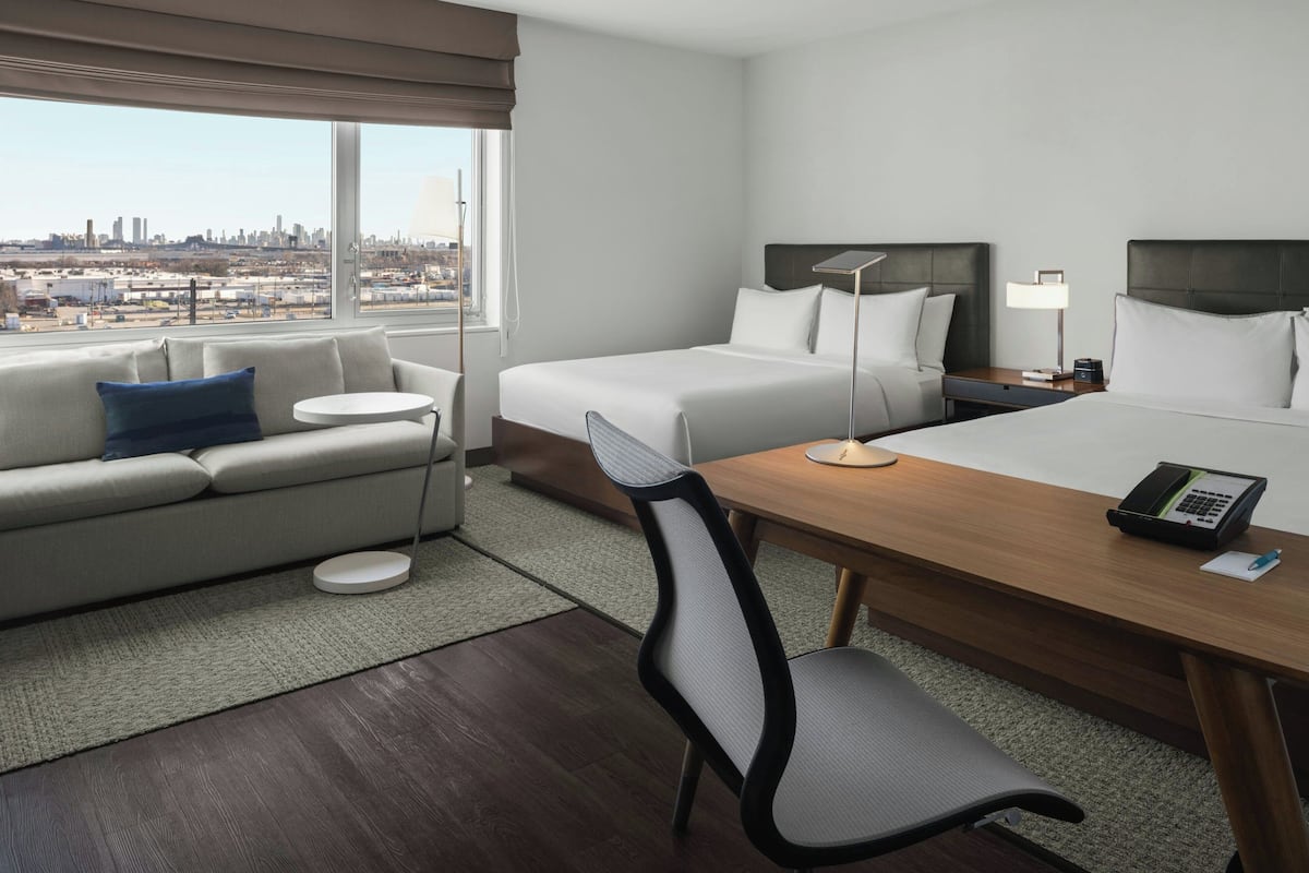 Habitación de hotel con cama, escritorio, silla, sofá y vista a la ciudad.