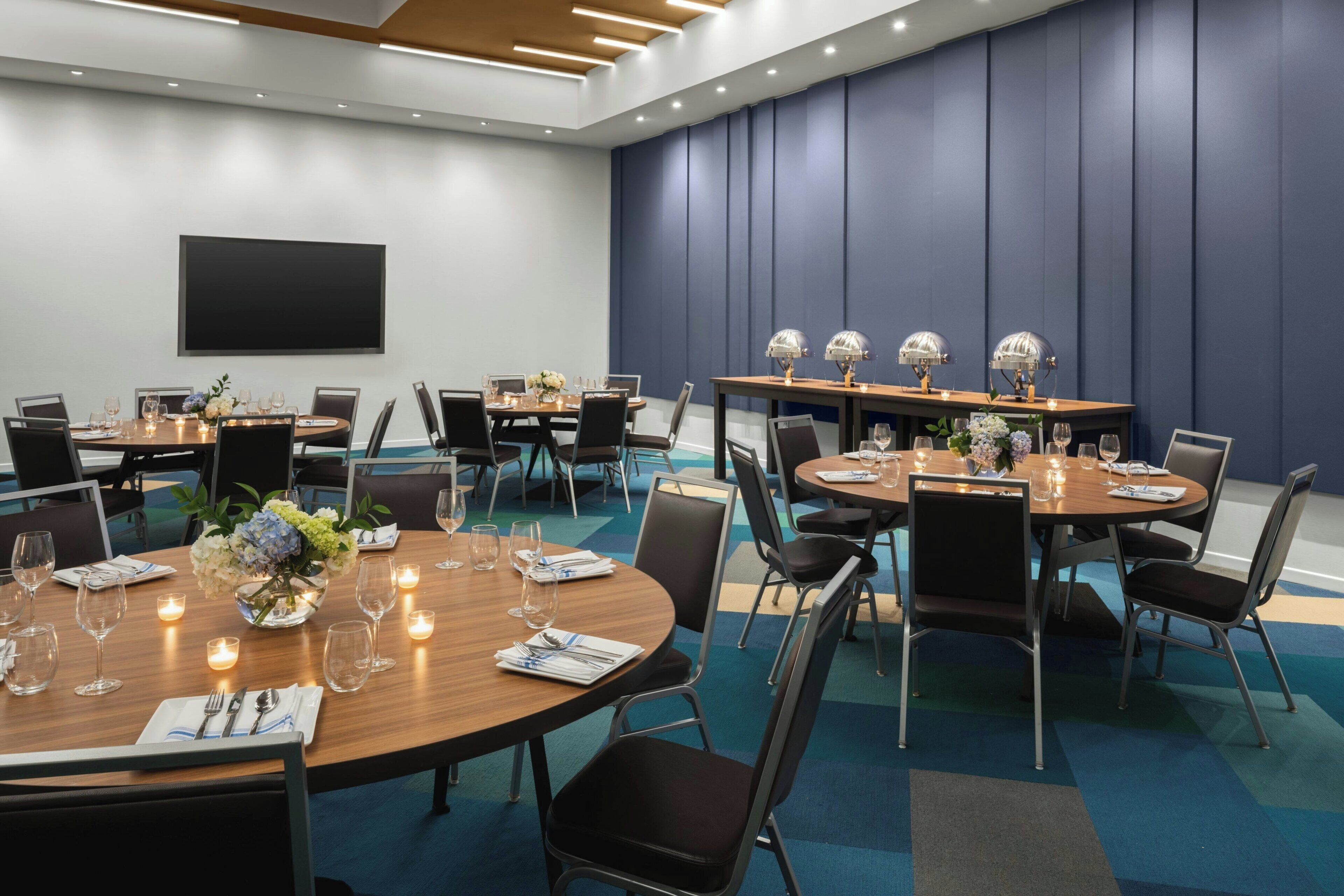 Une salle de conférence équipée de plusieurs tables, de chaises et d’un grand écran.