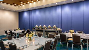 A conference room with multiple tables set for dining, equipped with chairs, tables, and decorative centerpieces.