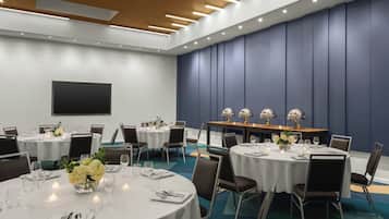A conference room with round tables, chairs, and a large screen.