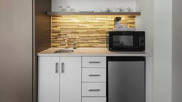 A compact kitchen with a microwave, dishwasher, and a tiled backsplash.