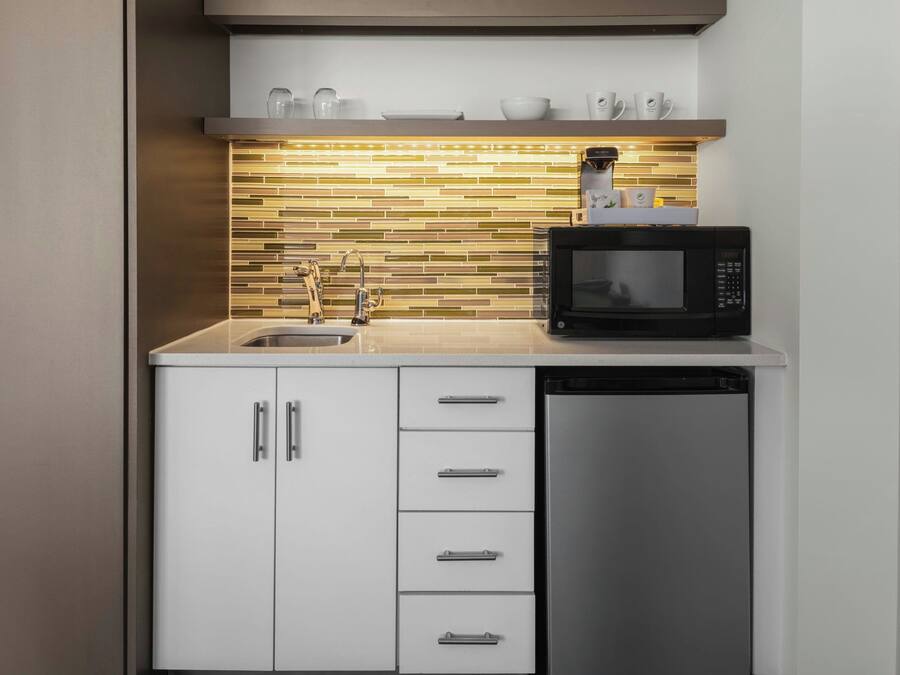 A compact kitchen with a microwave, dishwasher, and a tiled backsplash.