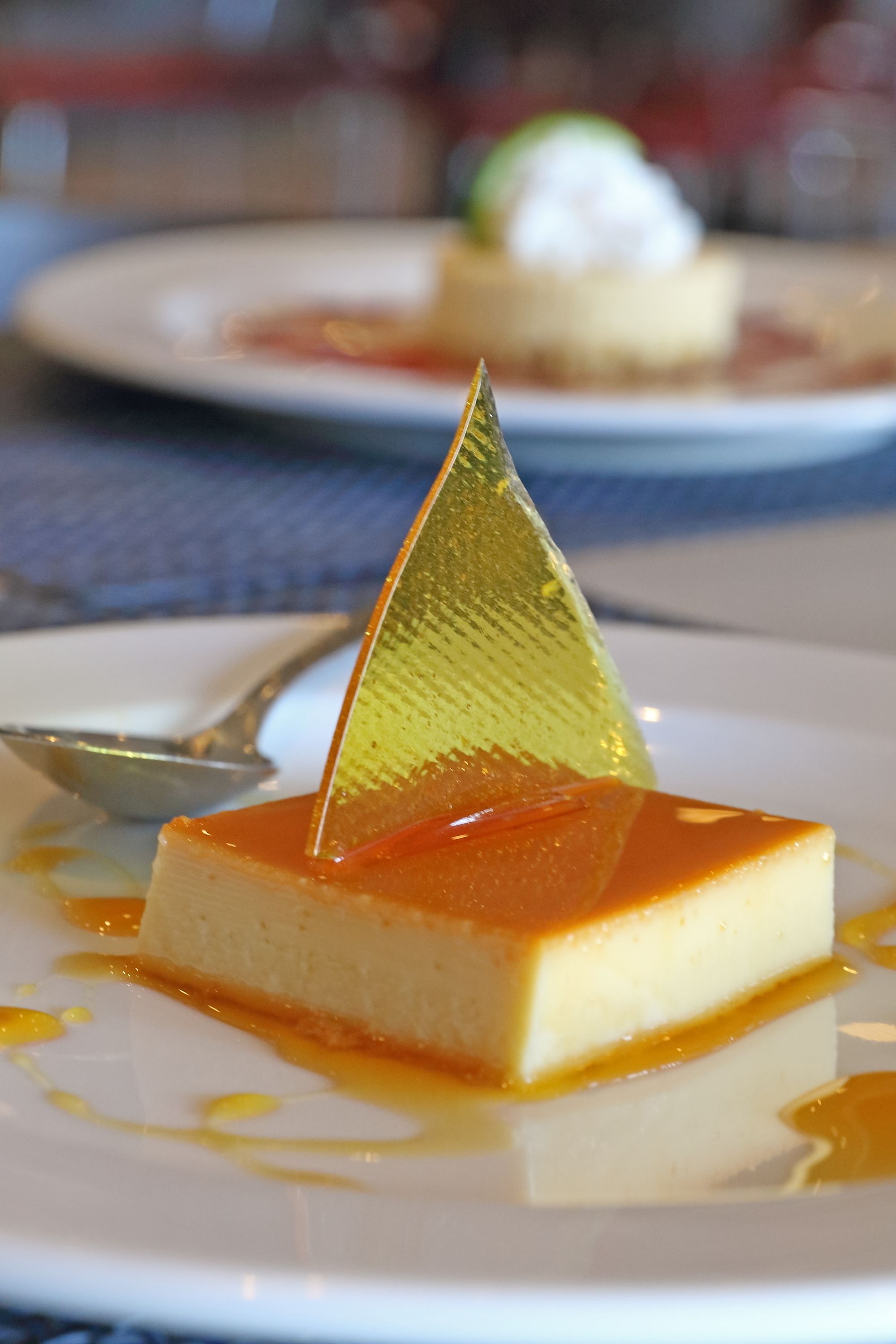 A dessert on a plate with a golden triangular garnish.