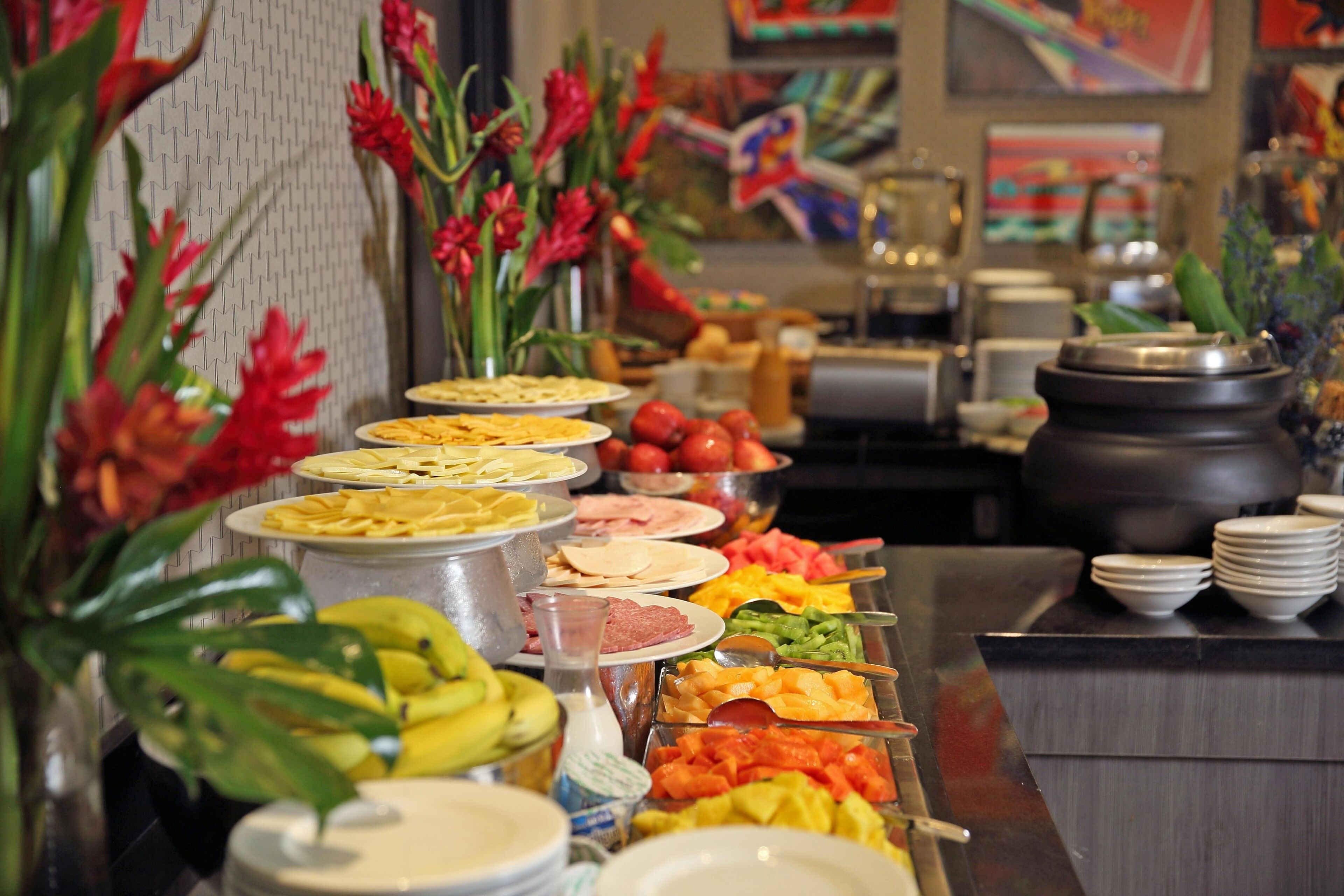 Un bufé con diferentes alimentos y una pared decorativa con flores.