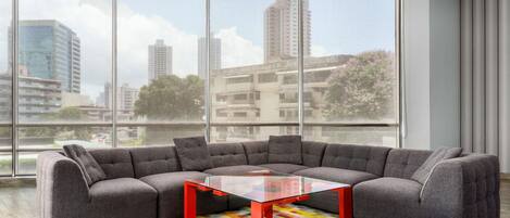 Una sala de estar moderna con un sofá modular, una mesa de centro de vidrio y una alfombra colorida.