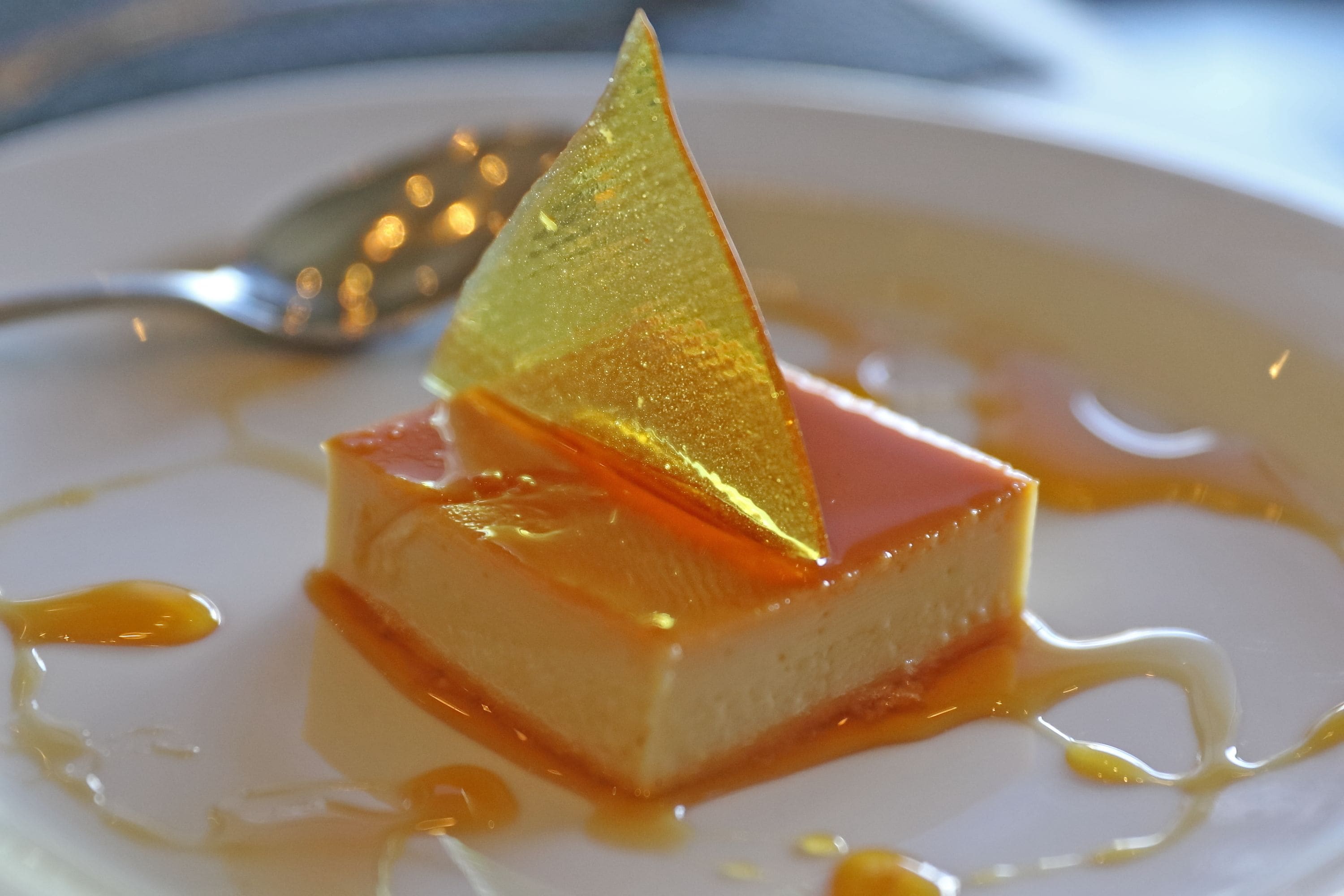 Un postre con un detalle dorado triangular sobre un plato blanco.