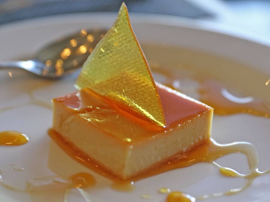 Un postre con un detalle dorado triangular sobre un plato blanco.