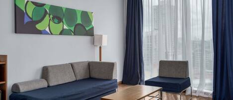 Una sala moderna con un sofá, una butaca, una mesa de centro y un cuadro abstracto grande en la pared.