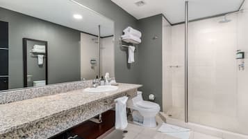 Un baño moderno con dos lavamanos, un espejo grande, un inodoro y una ducha con cerramiento de vidrio.