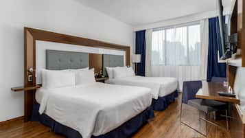 Hotelkamer met twee bedden, een bureau, een stoel, een televisie en een raam met gordijnen.