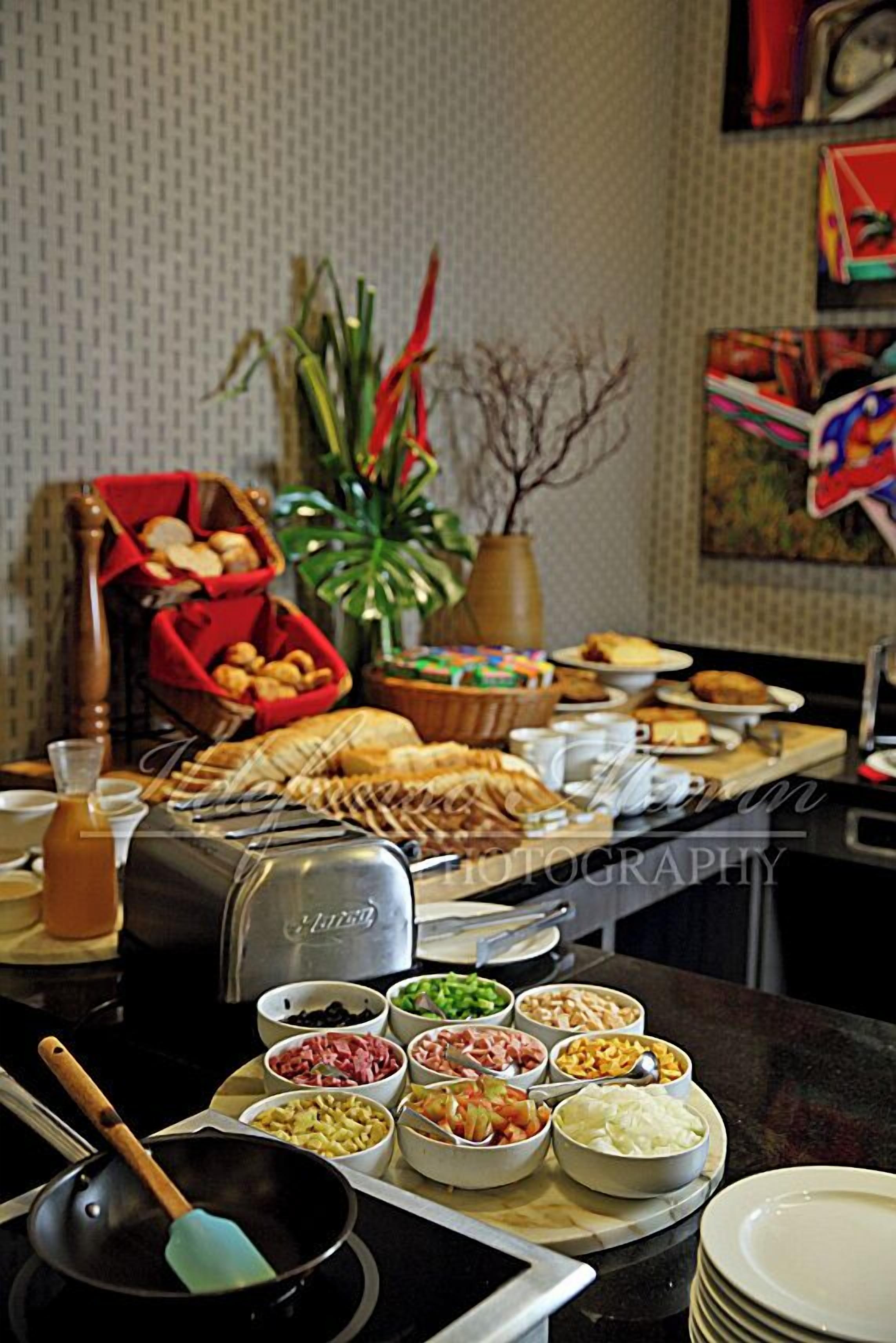 Uma mesa de buffet com diversos alimentos e uma torradeira.
