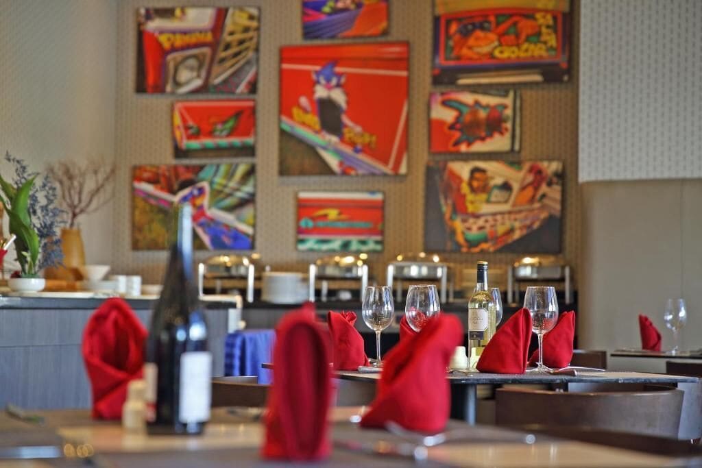 A restaurant with tables set for dining, featuring red napkins and wine glasses.