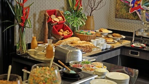 Een buffetopstelling met diverse gerechten, waaronder brood, gebak en een verscheidenheid aan schalen met eten.