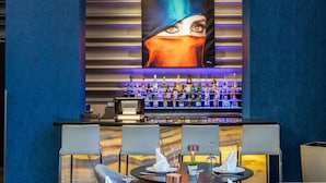Een bar met verschillende drankflessen, een toonbank en zitplaatsen met tafels en stoelen.