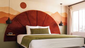 A modern bedroom with a large bed, a bench, a nightstand, and a wall mural.