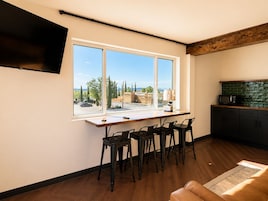 Una cocina moderna con un ventanal grande, un comedor con sillas y un televisor de pantalla plana en la pared.